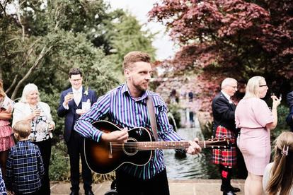 Outdoor garden wedding ceremony with seated guests and blossom on the trees