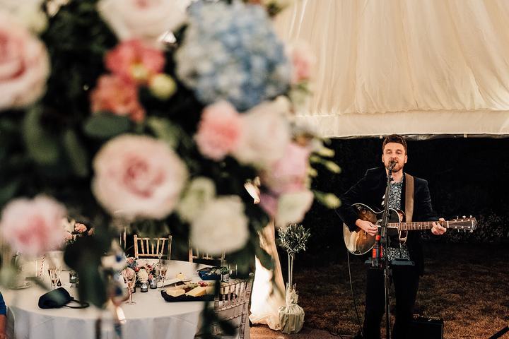 Wide view of a wedding marquee with pink and blue flowers in the foreground