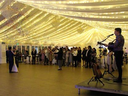 Tom Ryder performing in the marquee at Betty and Eric's wedding at Parklands Quendon Hall, warm golden light