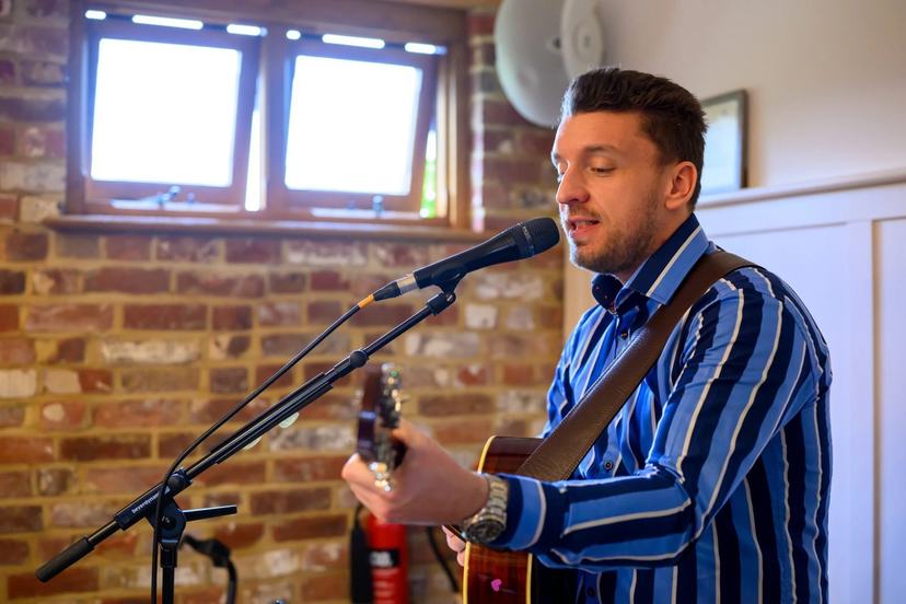 Tom Ryder singing in a brick-walled venue room.