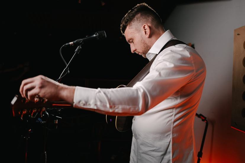 Tom Ryder reaching down to his loop pedal while playing.