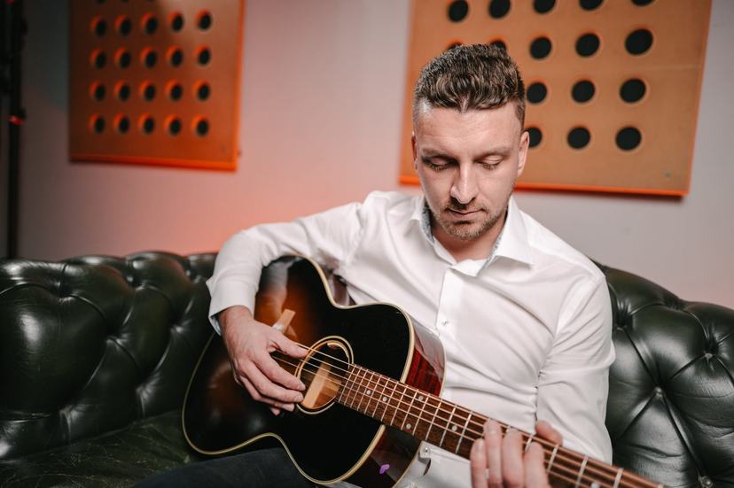 Tom Ryder seated with an acoustic guitar.